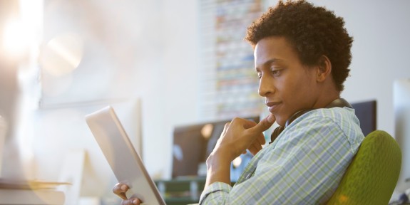 Mann sitzt mit Tablet in seinem Sessel